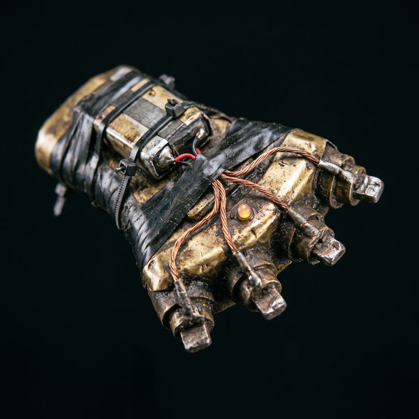 Rusty brass knuckles with a zip-tied battery